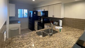 A compact kitchen with granite countertops, a stainless steel sink, a refrigerator, a microwave, and a toaster. - Bright and spacious 3 bedroom, 4th Floor unit (Sarasota)