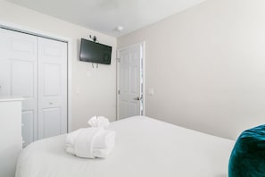 Ein Hotelzimmer mit einem Bett, einem an der Wand befestigten Flachbildfernseher und einer Tür zu einem Schrank.