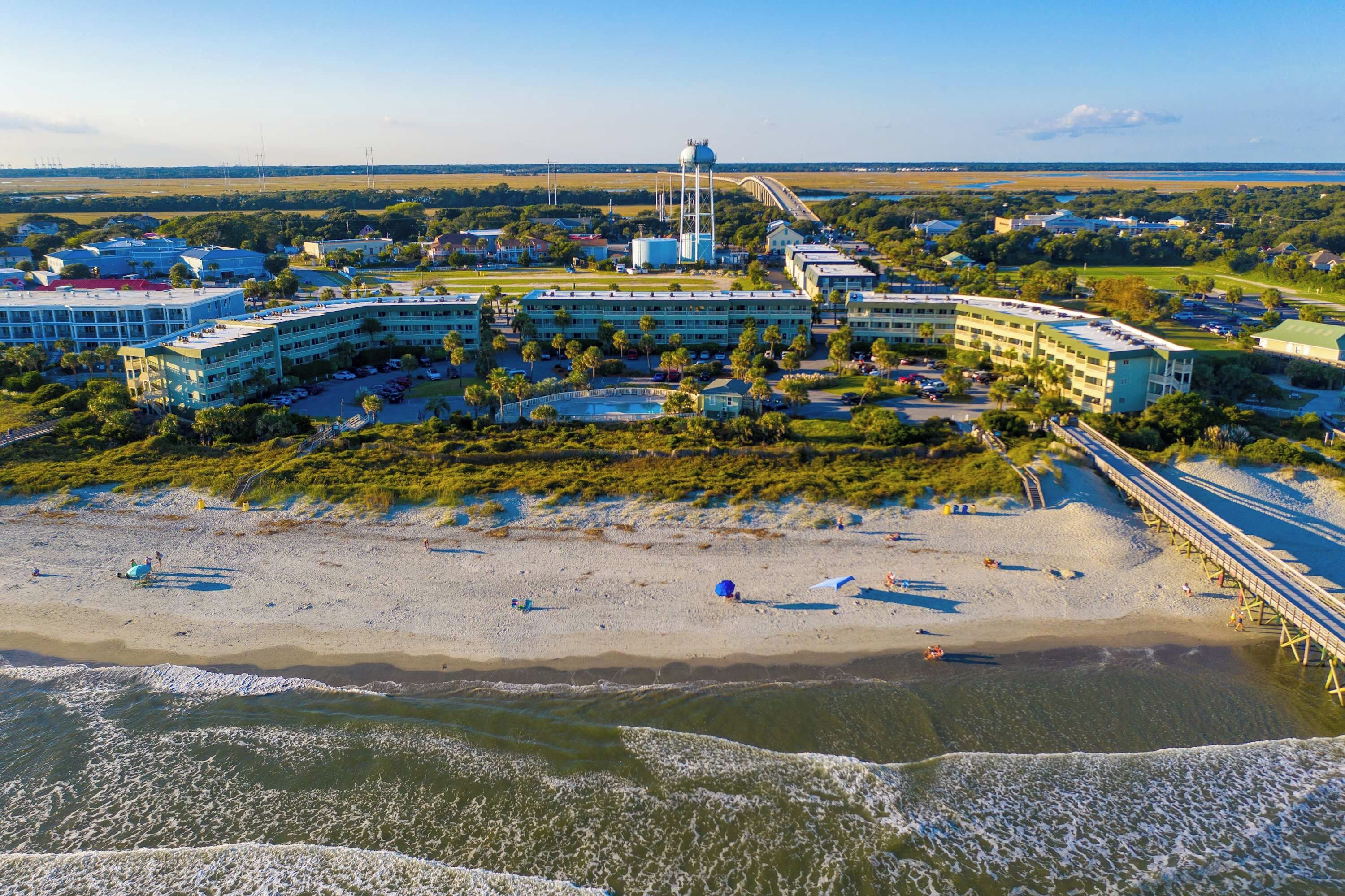 A coastal hotel with multiple buildings, a beach, and a pier.