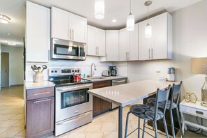A modern kitchen with stainless steel appliances, white cabinetry, and a central island with bar stools.
