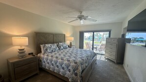 Une chambre à coucher comprenant un lit, des tables de chevet, une commode et un ventilateur de plafond.