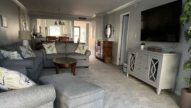 A spacious living room with a grey sofa set, a coffee table, and a TV mounted on the wall. - Beautiful Beachfront 1st Floor condo (Sarasota)