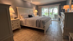 A bedroom with a bed, nightstands, a dresser, and a view of the outdoors. - Beautiful Beachfront 1st Floor condo (Sarasota)