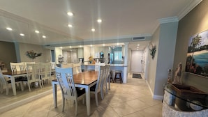 A modern kitchen with a central island, white cabinetry, and a dining area with a wooden table and white chairs.