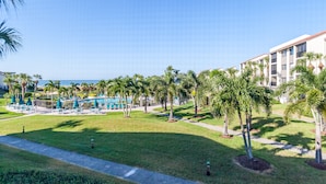 A resort with a pool area, palm trees, and a view of the ocean.