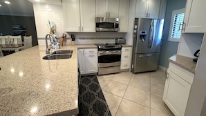 A modern kitchen with granite countertops, stainless steel appliances, and white cabinetry.