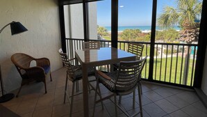 A balcony with a table and chairs, a ceiling fan, and a view of the ocean. - Beachfront  2 bed/ 2 Bath Condo (Sarasota)
