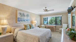 A bedroom with a bed, nightstands, a desk, a chair, a ceiling fan, and a window with blinds. - Spacious and Bright Gulf front 2 bed/2 bath condo (Sarasota)