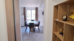 Un pasillo que conduce a un comedor con una mesa y sillas, un estante de madera con objetos decorativos y una puerta corredera.