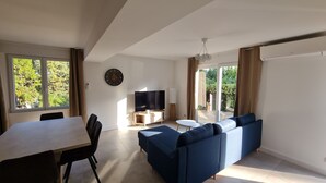 Una sala de estar moderna con sofá, televisor y comedor.
