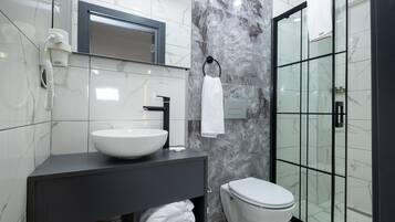 Ein modernes Badezimmer mit einem weißen Waschbecken, einer schwarzen Kommode und einer Duschkabine.