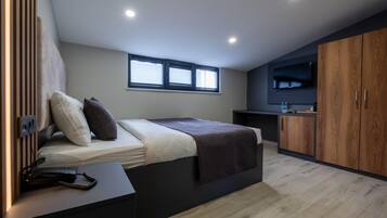 Un dormitorio moderno con una cama, mesita de noche y televisor montado en la pared.