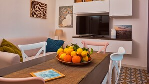 Un salon moderne comprenant une table à manger, des chaises, un téléviseur et des œuvres d’art accrochées aux murs.