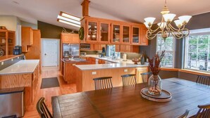 A spacious kitchen with wooden cabinets, a central island, and a dining area with a chandelier. - 3.3k Sqft, Arcade, Views, EV, Pinecrest & Dodge Ridge (Twain Harte)