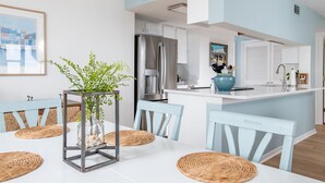Una cocina moderna con armarios blancos, un refrigerador de acero inoxidable e una isla azul con pileta.