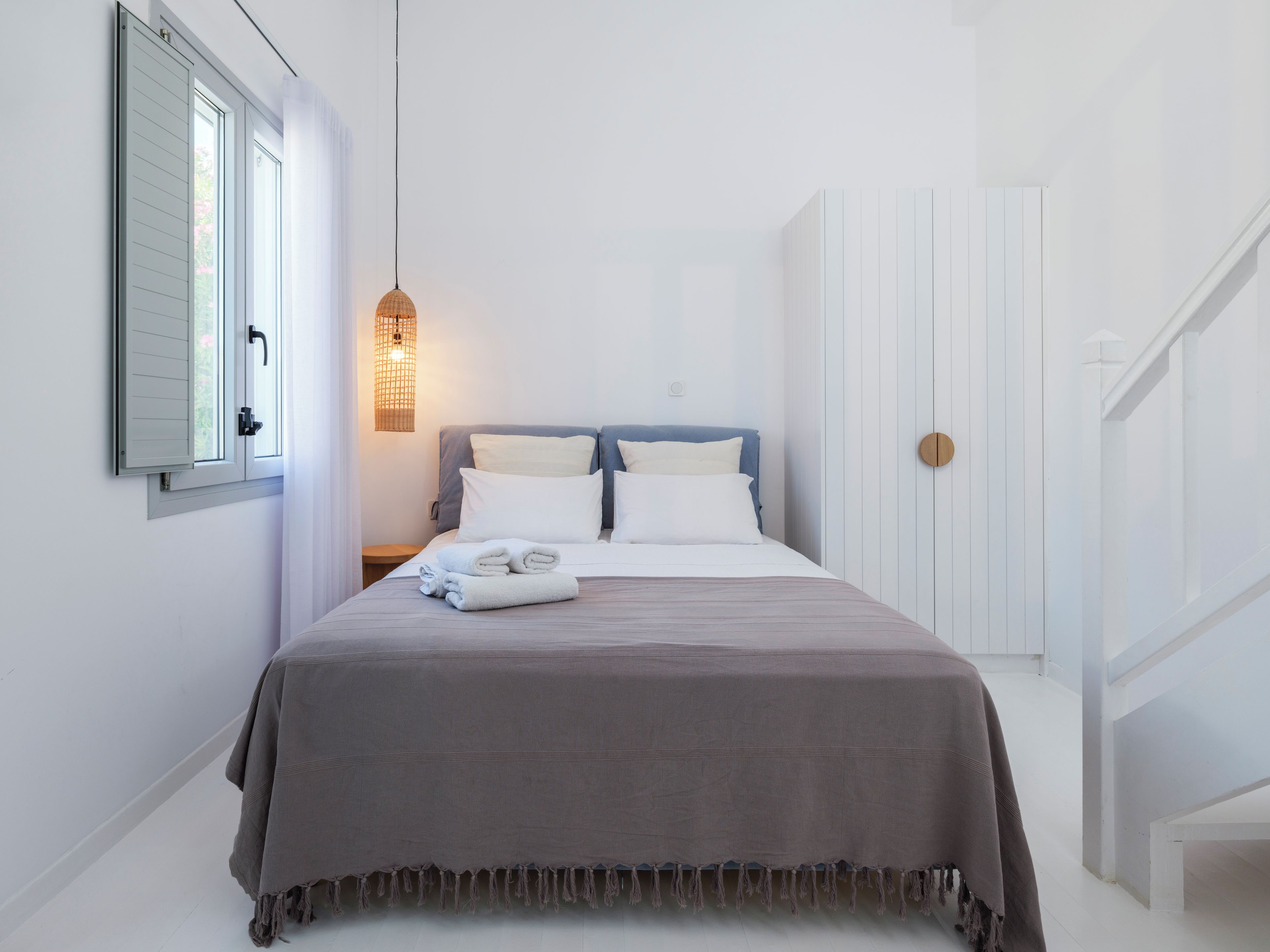 Une chambre d’hôtel avec un lit, une table de chevet, une lampe fixée au mur et une porte.