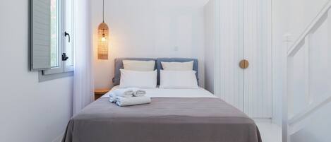 Une chambre d’hôtel avec un lit, une table de chevet, une lampe fixée au mur et une porte.