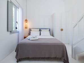 A hotel room with a bed, a nightstand, a wall-mounted lamp, and a door.