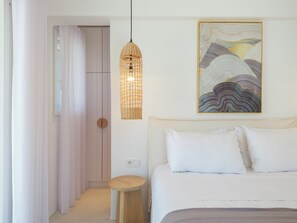 Une chambre à coucher comprenant un lit, une table de chevet, un luminaire suspendu et un tableau accroché au mur.