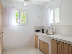 A modern kitchen with a sink, cabinets, and a window with curtains.
