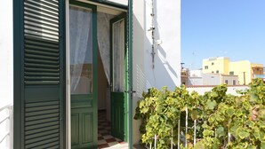Une entrée d’immeuble avec une porte verte, un sol à carreaux et une clôture recouverte de lierre.