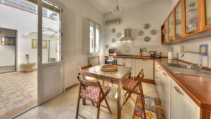 Une cuisine avec une table à manger, des chaises et une grande fenêtre.