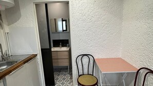 A compact kitchen with a sink, wooden countertop, and a dining area with two chairs and a table. - T2 Plein Centre D'arcachon au Calme. Animaux Acceptés (Arcachon)