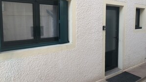 A building facade with a textured exterior, a window with a dark frame, and a door with a dark frame. - T2 Plein Centre D'arcachon au Calme. Animaux Acceptés (Arcachon)