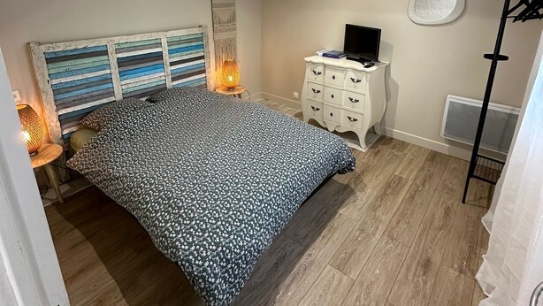 A bedroom with a bed, bedside lamps, a dresser, a TV, and a deer head decoration. - T2 Plein Centre D'arcachon au Calme. Animaux Acceptés (Arcachon)