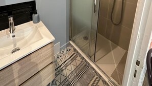 A modern bathroom with a glass-enclosed shower, a vanity with a mirror, and a tiled floor. - T2 Plein Centre D'arcachon au Calme. Animaux Acceptés (Arcachon)