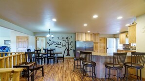 A spacious kitchen with wooden cabinets, a central island with bar stools, and a decorative tree mural on the wall. - Custer Connection- Private Retreat: 6-Acre Nature Escape with Trail Access, Custer. (Custer)