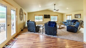 A spacious living room with a wooden floor, a ceiling fan, and a large window. - Custer Connection- Private Retreat: 6-Acre Nature Escape with Trail Access, Custer. (Custer)