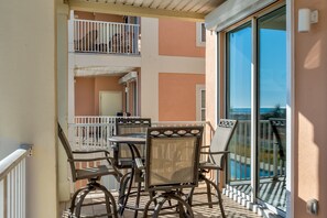 Un balcone con tavolo e sedie, vista su una piscina e un edificio dalle pareti color pesca.