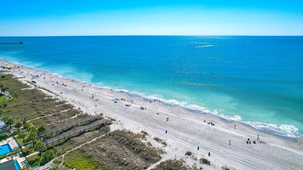 A beach with a wooden walkway, a pool, and a clear view of the ocean. - Oceanfront Blockade Runner Villa - Pool (North Myrtle Beach)