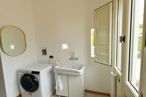 A compact laundry room with a washing machine, a sink, and a mirror. - Vacation home with private pool, Floridia (Floridia)