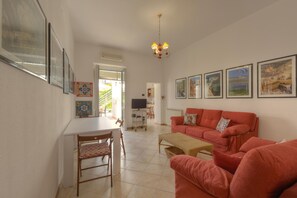 A living room with a red sofa, a dining table with chairs, and a television.
