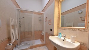 Un baño con ducha de vidrio, lavamanos e inodoro.