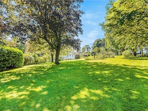 A well-maintained grassy area with mature trees and a clear sky.