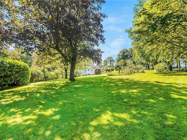 A well-maintained grassy area with mature trees and a clear sky.