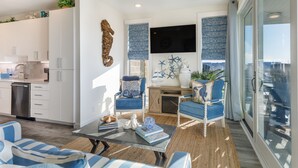 A modern living space with a kitchen, seating area, and large windows. - Golf Cart Boardwalk to the Beach, Resort Pools (Port Aransas)