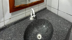 A bathroom with a black granite sink, a wooden-framed mirror, and white tiled walls. - Pousada e Restaurante do Francisco (Icapuí)