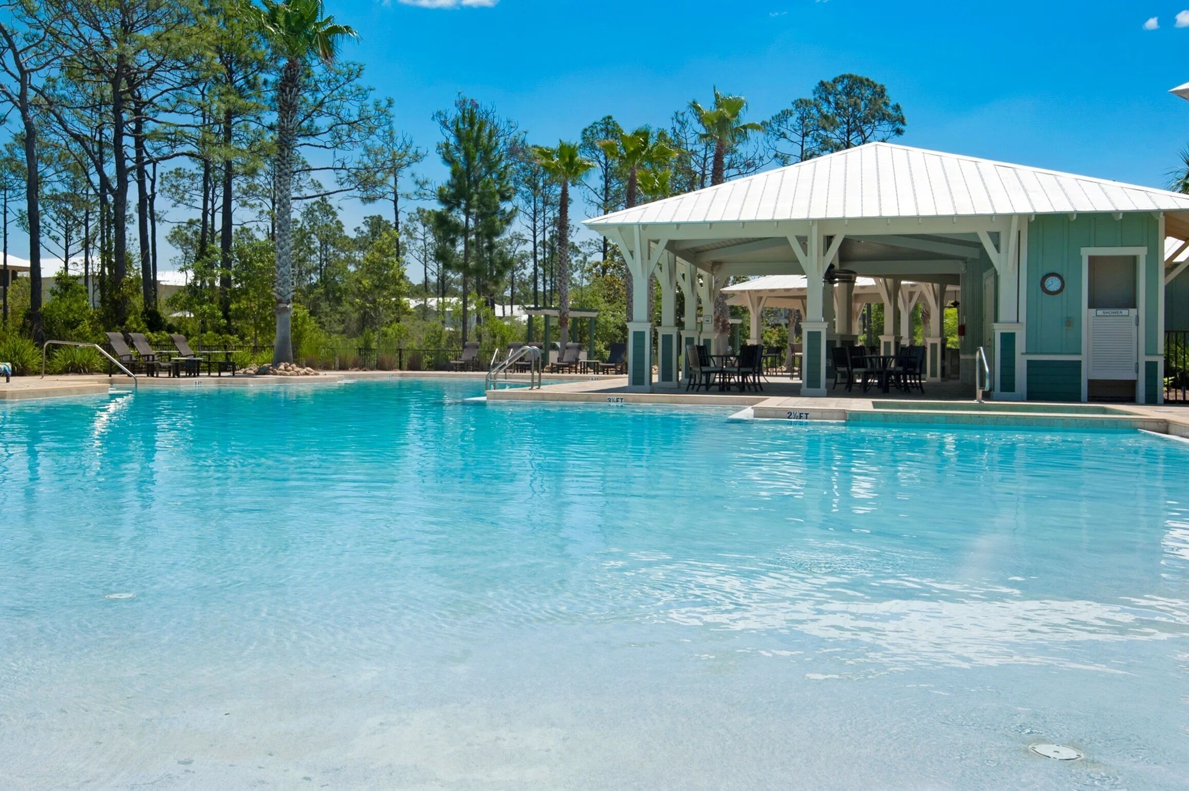 A clear blue pool with lounge chairs and a covered pavilion.
