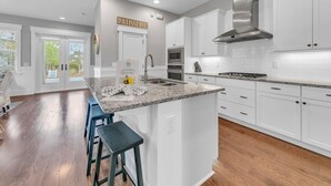 A modern kitchen with white cabinetry, a granite countertop, and a stainless steel range hood. - ⛵6-Seater Golf Cart🚙Beach + Nature Trails in 30A-Sail Away⛵ (Santa Rosa Beach)
