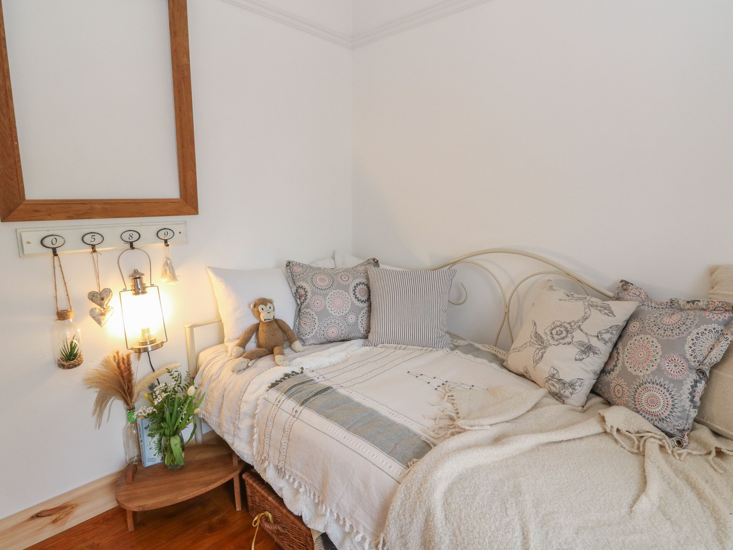 Ein ordentlich eingerichtetes Schlafzimmer mit einem Bett, Kissen, einem Nachttisch mit Lampe und Wandleuchten.