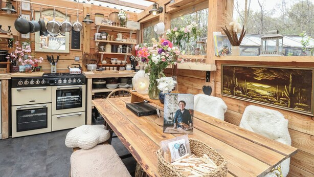 A rustic kitchen with wooden beams, a stove, and various kitchen utensils. - The Cottage In The Woods (Taynuilt)