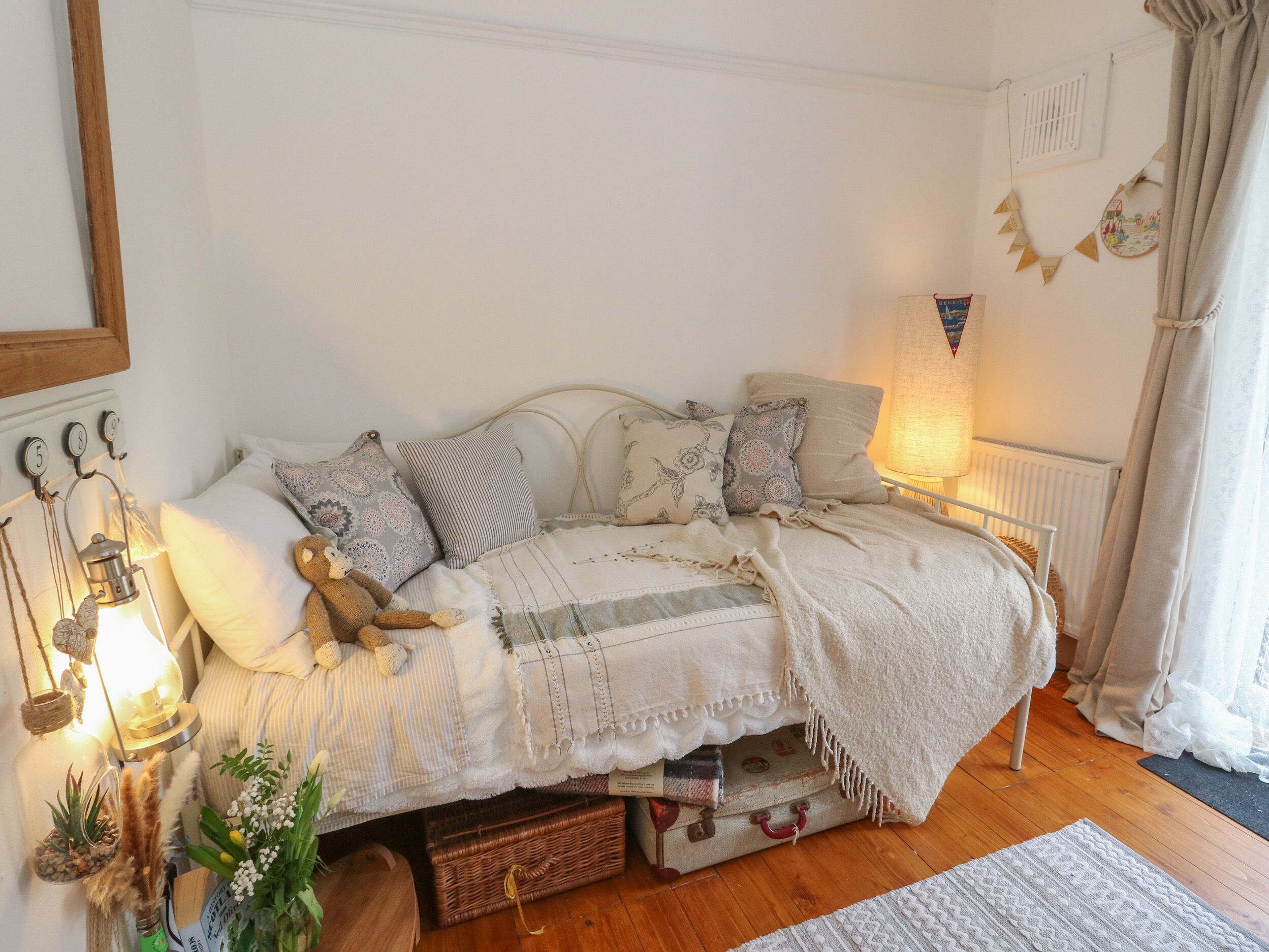 A cozy bedroom with a bed, pillows, a teddy bear, a lamp, and decorative items.