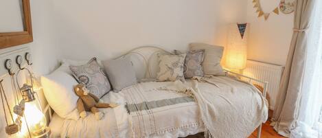 A cozy bedroom with a bed, pillows, a teddy bear, a lamp, and decorative items.