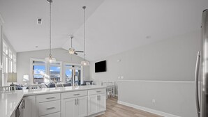 Una cocina moderna con una isla grande, luces colgantes e televisor integrado.