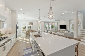 Un'ampia cucina con un'isola grande, elettrodomestici moderni e illuminazione a sospensione.
