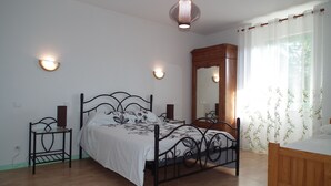 A bedroom with a bed, two bedside tables, a nightstand, a wooden dresser, a large mirror, and a window with curtains. - Maison Indépendante en Chartreuse (Saint-Laurent-du-Pont)